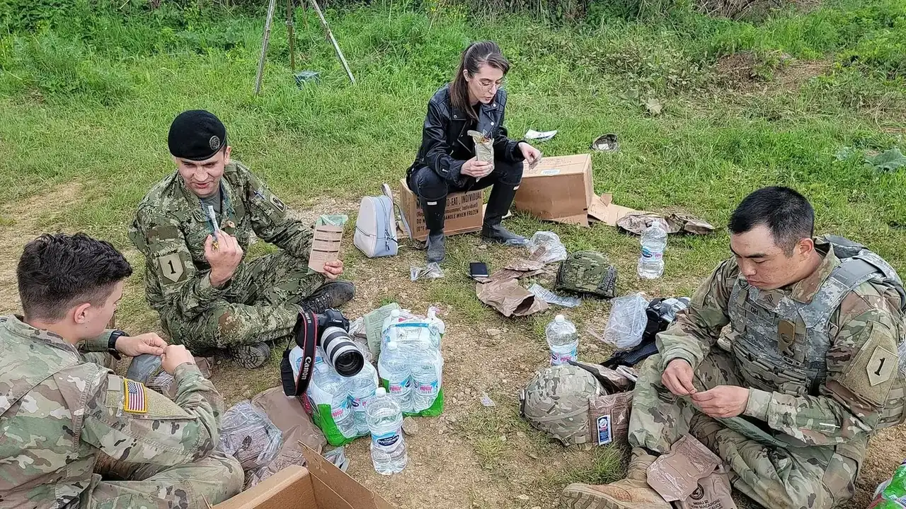 Des militaires font une pause sur le terrain, rations et matériel au sol